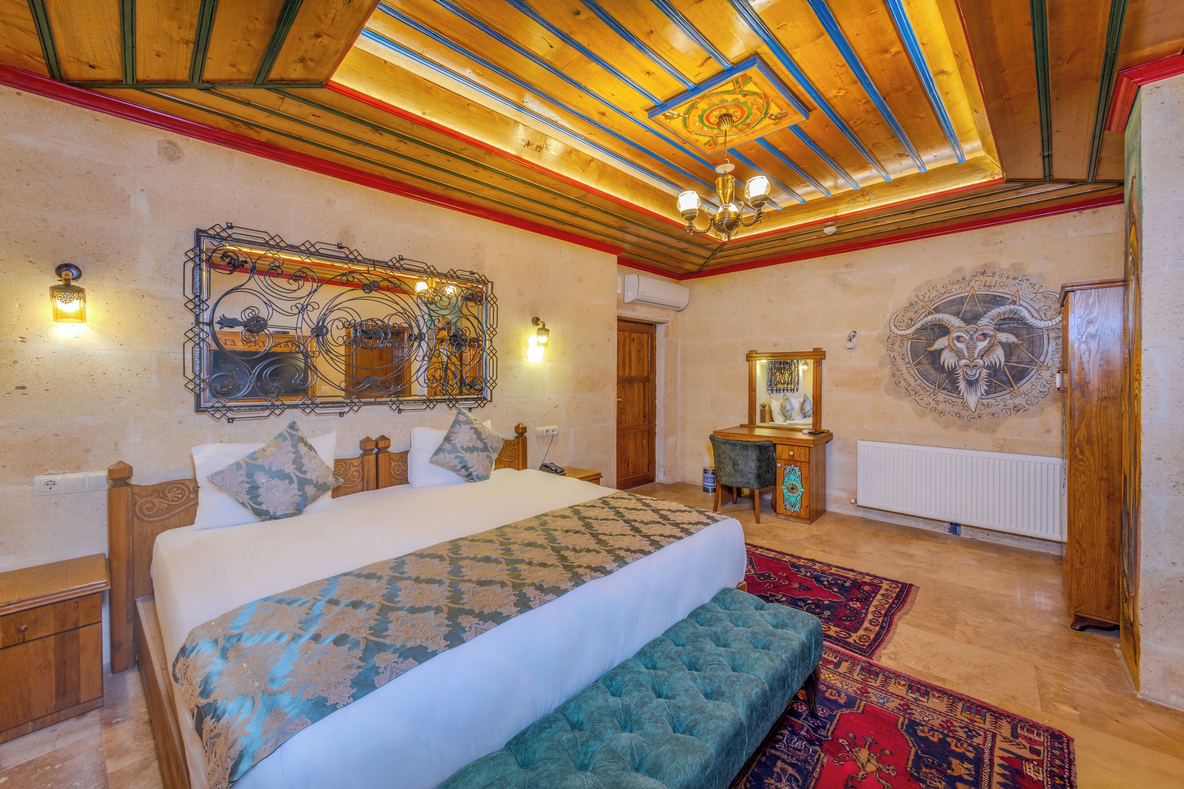 A spacious bedroom with a large bed, a bench, a wooden ceiling, and a decorative wall piece.