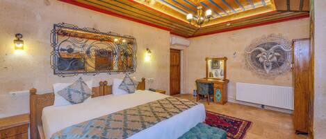A spacious bedroom with a large bed, a bench, a wooden ceiling, and a decorative wall piece.