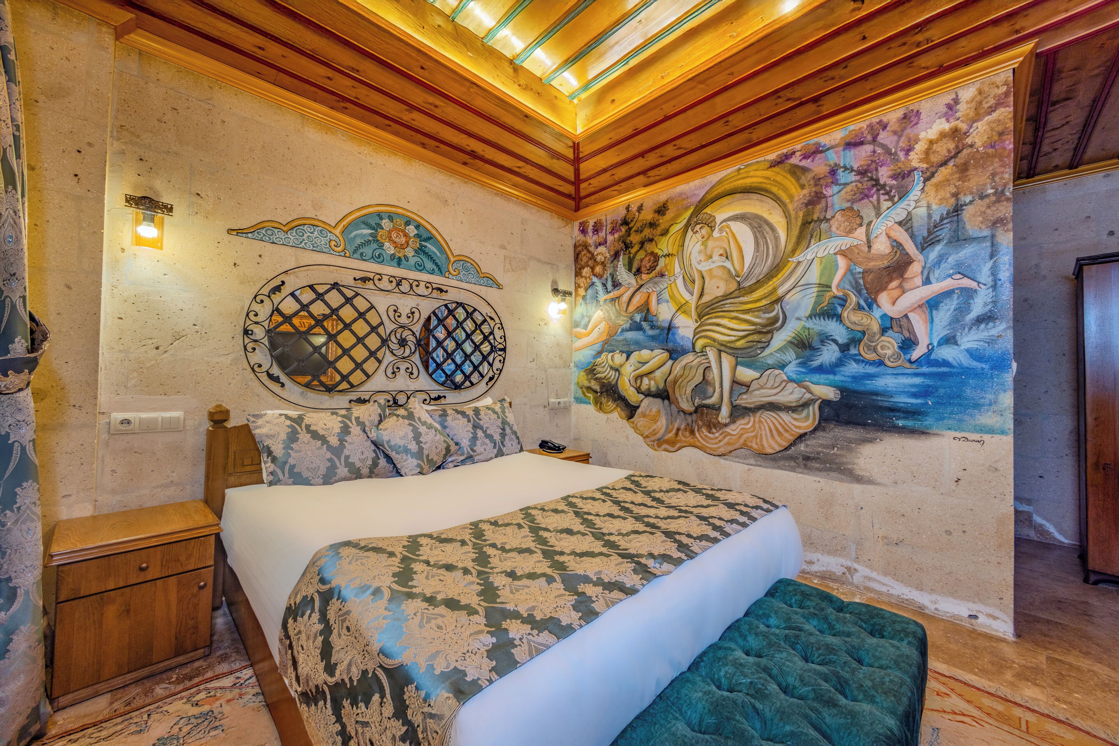 A bedroom with a bed, a nightstand, a wall mural, and a wooden ceiling.