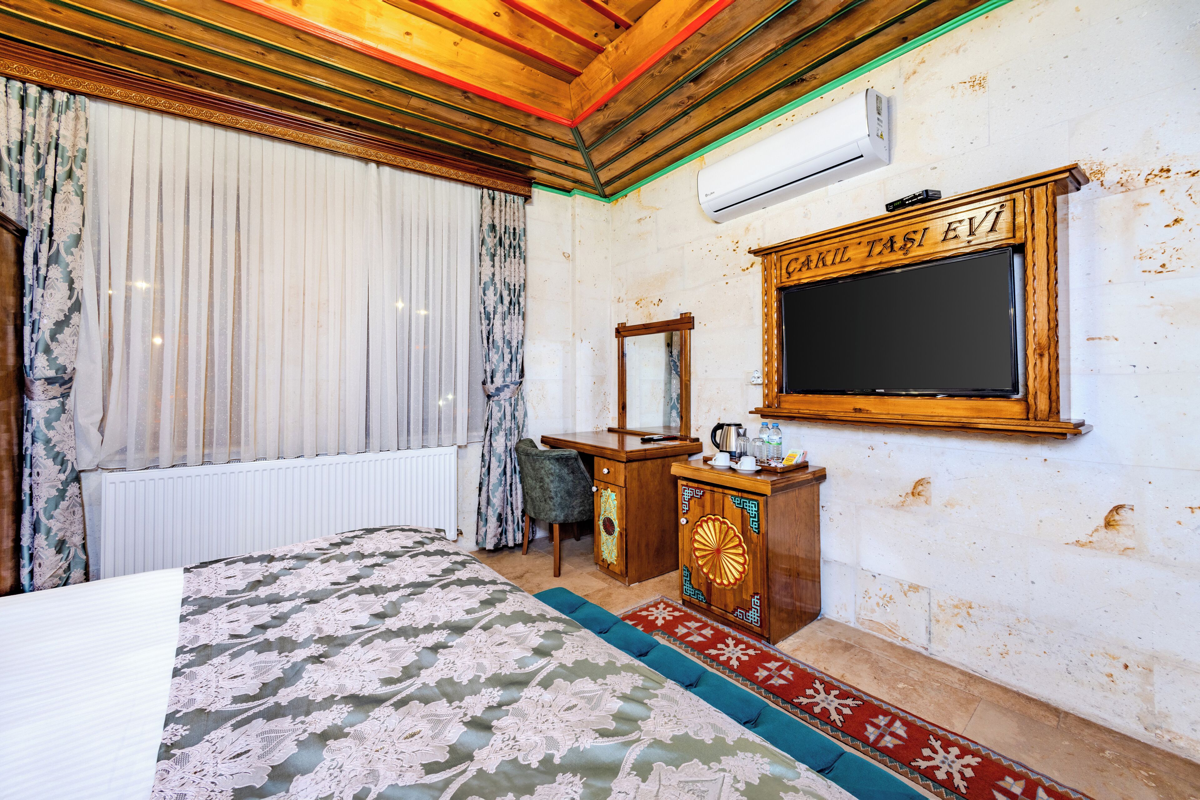 A room with a bed, a wooden cabinet, a mirror, and a television.