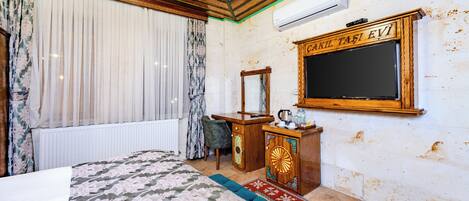 A room with a bed, a wooden cabinet, a mirror, and a television.