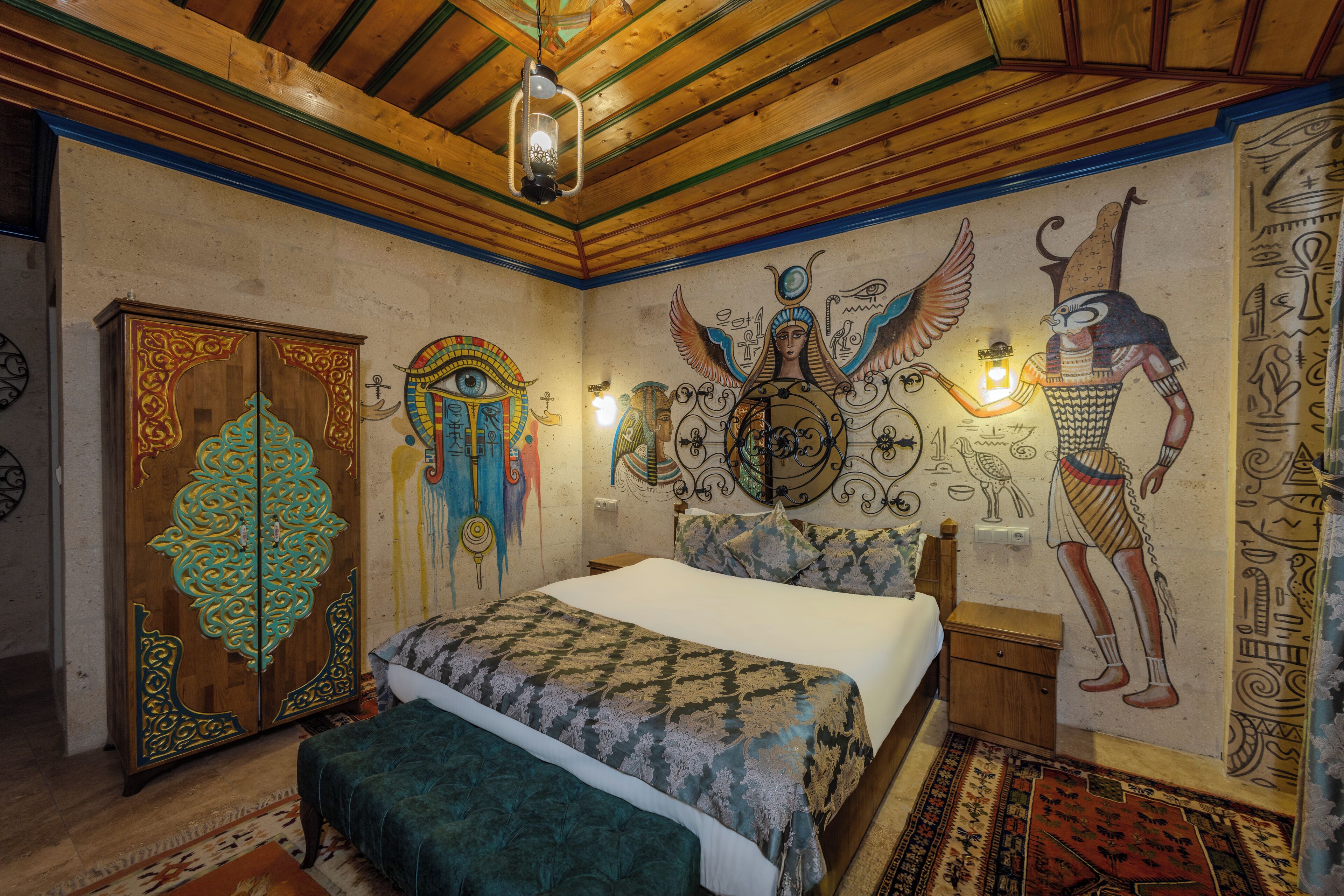 Una habitación con cama, armario y decoración mural con motivos egipcios.