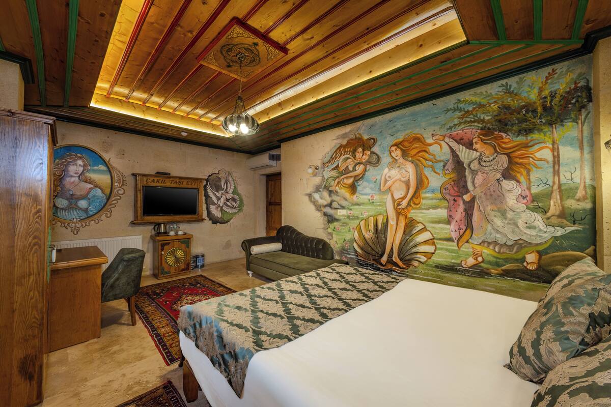 A room with a bed, a desk, a chair, a clock, and a mural on the wall.