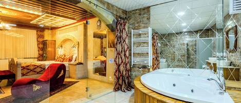Un baño moderno con una bañera grande, mampara de ducha de vidrio y tocador de madera.