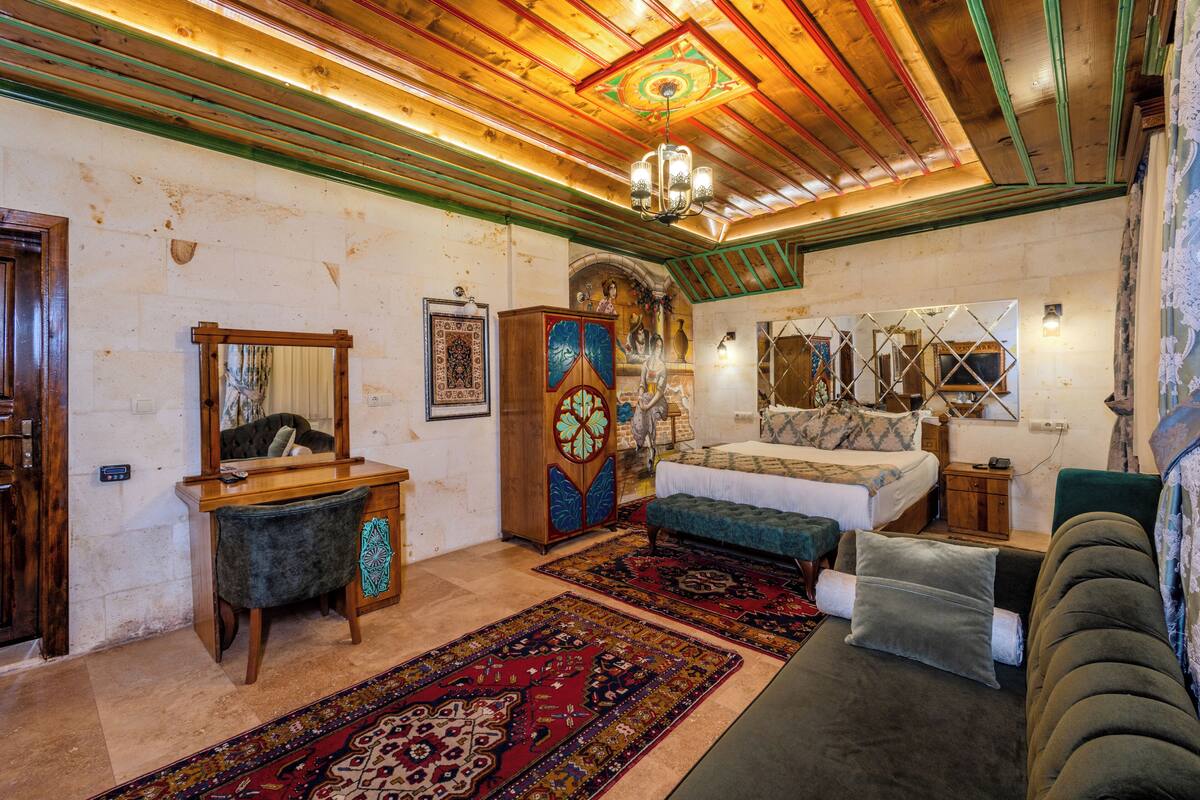 A traditional room with a bed, a sofa, a desk, and a mirror.