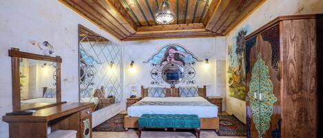 A bedroom with a wooden ceiling, a bed with a blue bedspread, a large mirror, and a decorative wall piece.