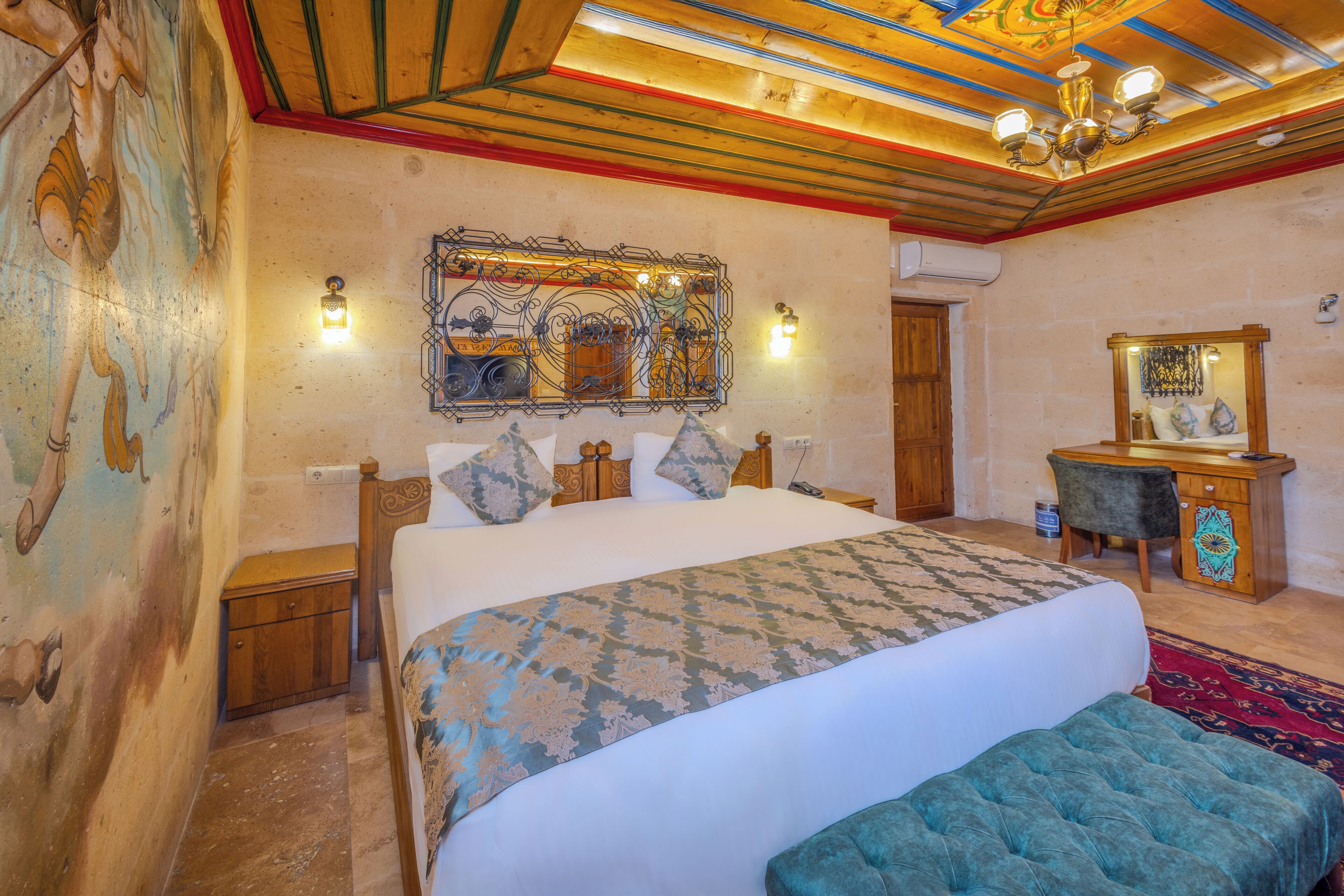A bedroom with a large bed, a wooden headboard, a nightstand, a dresser, a mirror, and a decorative ceiling.