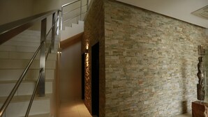 A staircase with metal railings leading to a landing with a stone wall and a wooden sculpture.