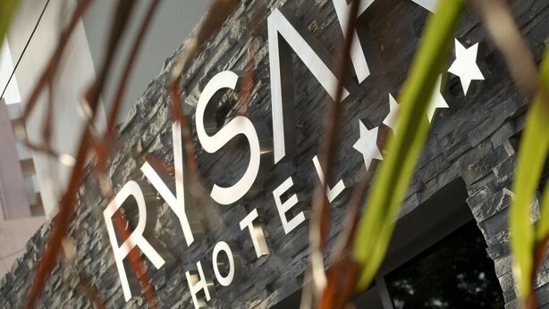 A hotel sign with the name "RYSAK HOTEL" and a stone facade.