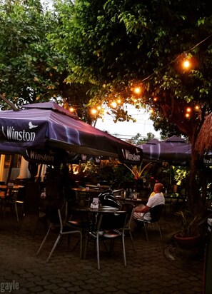 An outdoor seating area with tables and chairs under umbrellas labeled 'Winston'.