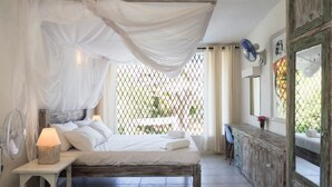 Un dormitorio con cama, mesita de noche, lámpara y ventana con vistas.