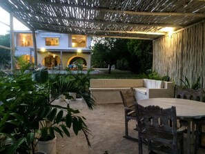 An outdoor patio area with a table and chairs, surrounded by potted plants and a seating area. - Baobab Beach House Bed & Breakfast (Diani Beach)