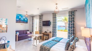 A hotel room with a bed, a sofa, a desk, and a TV. There is a balcony with a view of the sea. - Les Flots Bleus (Saint-Raphael)