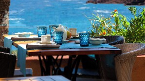 A table set with blue glassware, white plates, and a white pitcher, overlooking a coastal view. - Les Flots Bleus (Saint-Raphael)