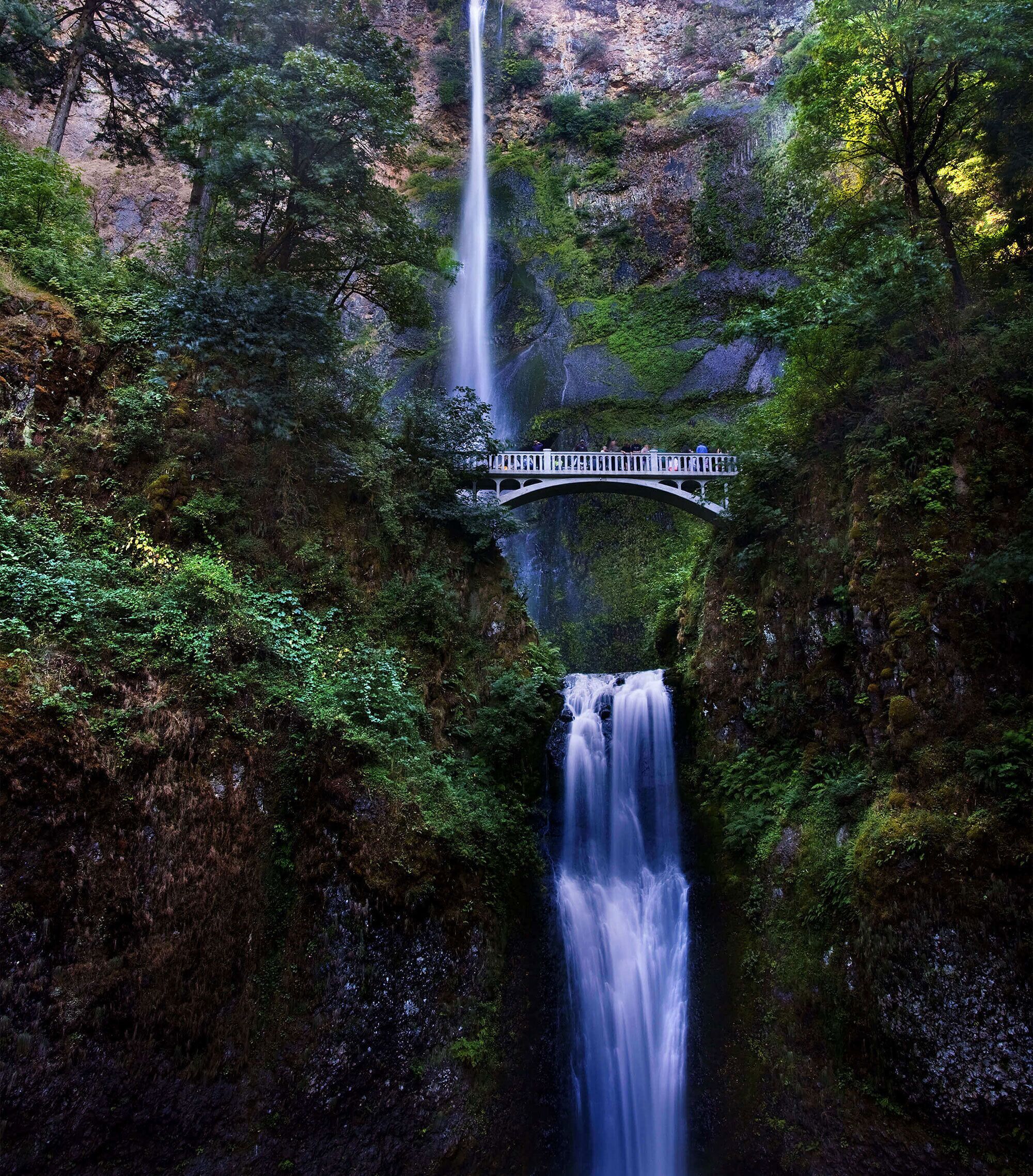 A waterfall cascading down a rocky cliff, with a bridge spanning across the water.