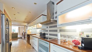 A modern kitchen with a stainless steel range hood, a coffee machine, and a breakfast bar. - The Brendan Gleeson Suite - hiphipstay (Dublin)