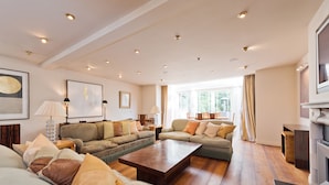 A spacious living room with a large sofa set, a coffee table, and a television. - The Brendan Gleeson Suite - hiphipstay (Dublin)