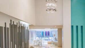 Ein modernes Interieur mit einem Ecksofa, einem türkisfarbenen Teppich und einer wandmontierten Leuchte.