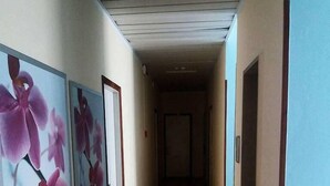 Un couloir doté d’un plancher en bois et de portes des deux côtés, menant à différentes pièces.