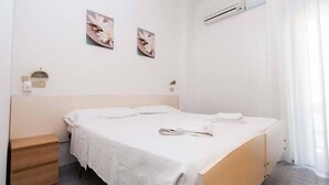 Une chambre à coucher épurée et minimaliste, avec un lit simple, une table de chevet en bois et une petite table d’appoint.