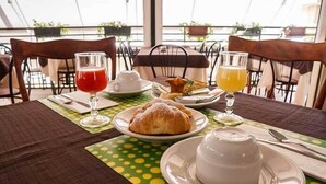 Une table de petit-déjeuner avec des croissants, une tasse de café et un verre de jus d’orange.