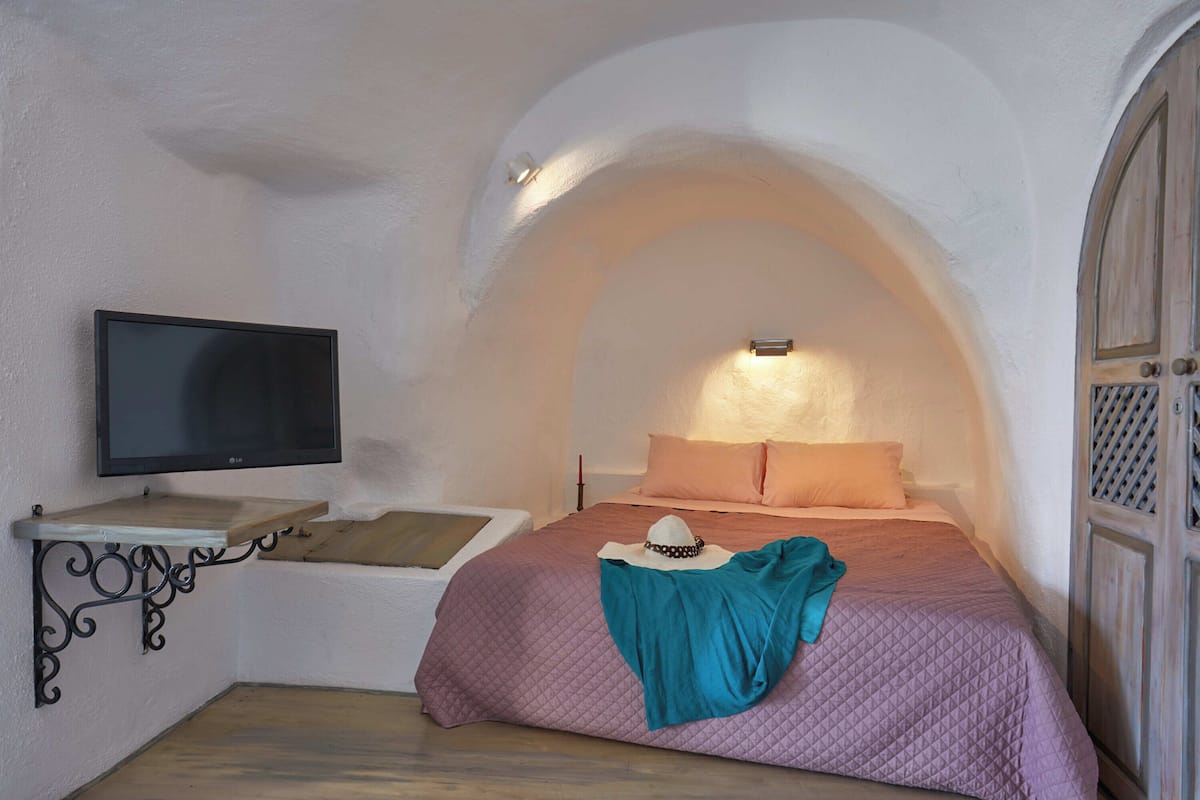 A bedroom with a bed, a television, and a small shelf.