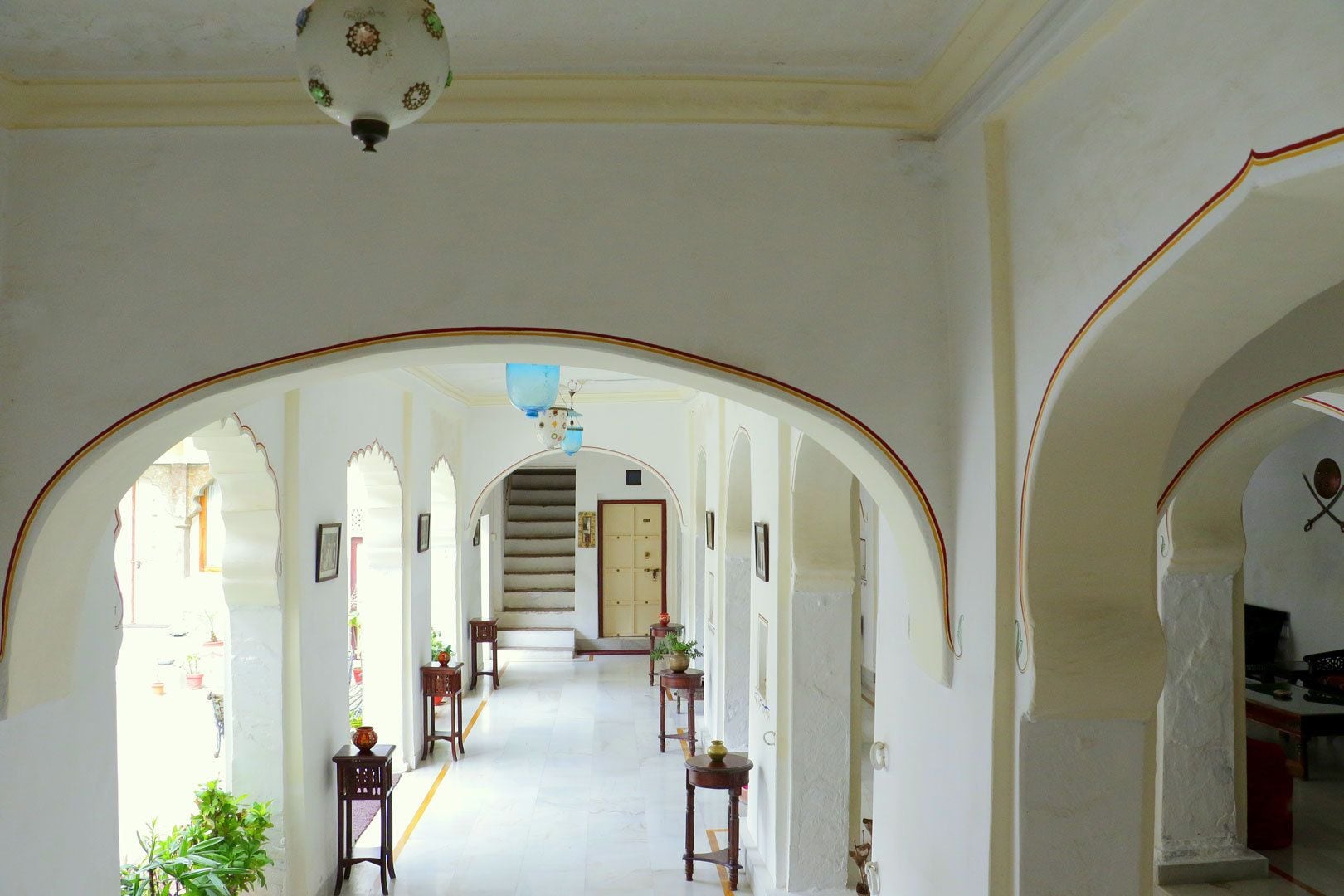 A corridor with arches, a staircase, and a chandelier.