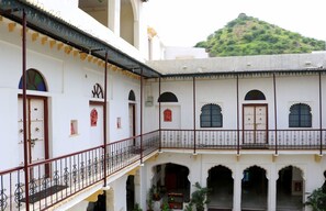 A traditional building with a courtyard, arched doorways, and a balcony with a metal railing.