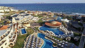 Resort com várias piscinas, guarda-sóis e uma grande piscina central com estrutura em cúpula.