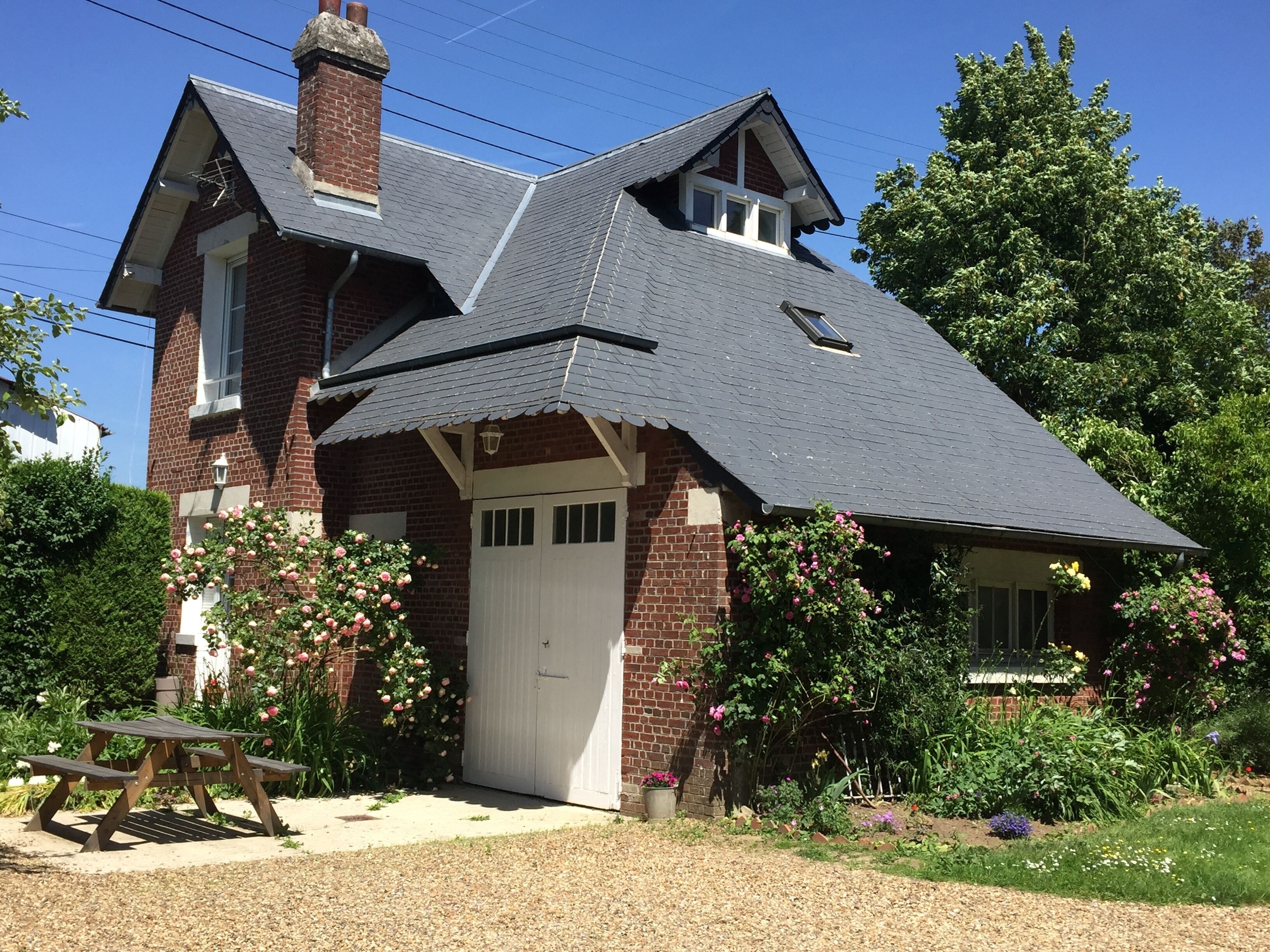 A two-story brick house with a steeply pitched roof, a white front door, and a small porch.