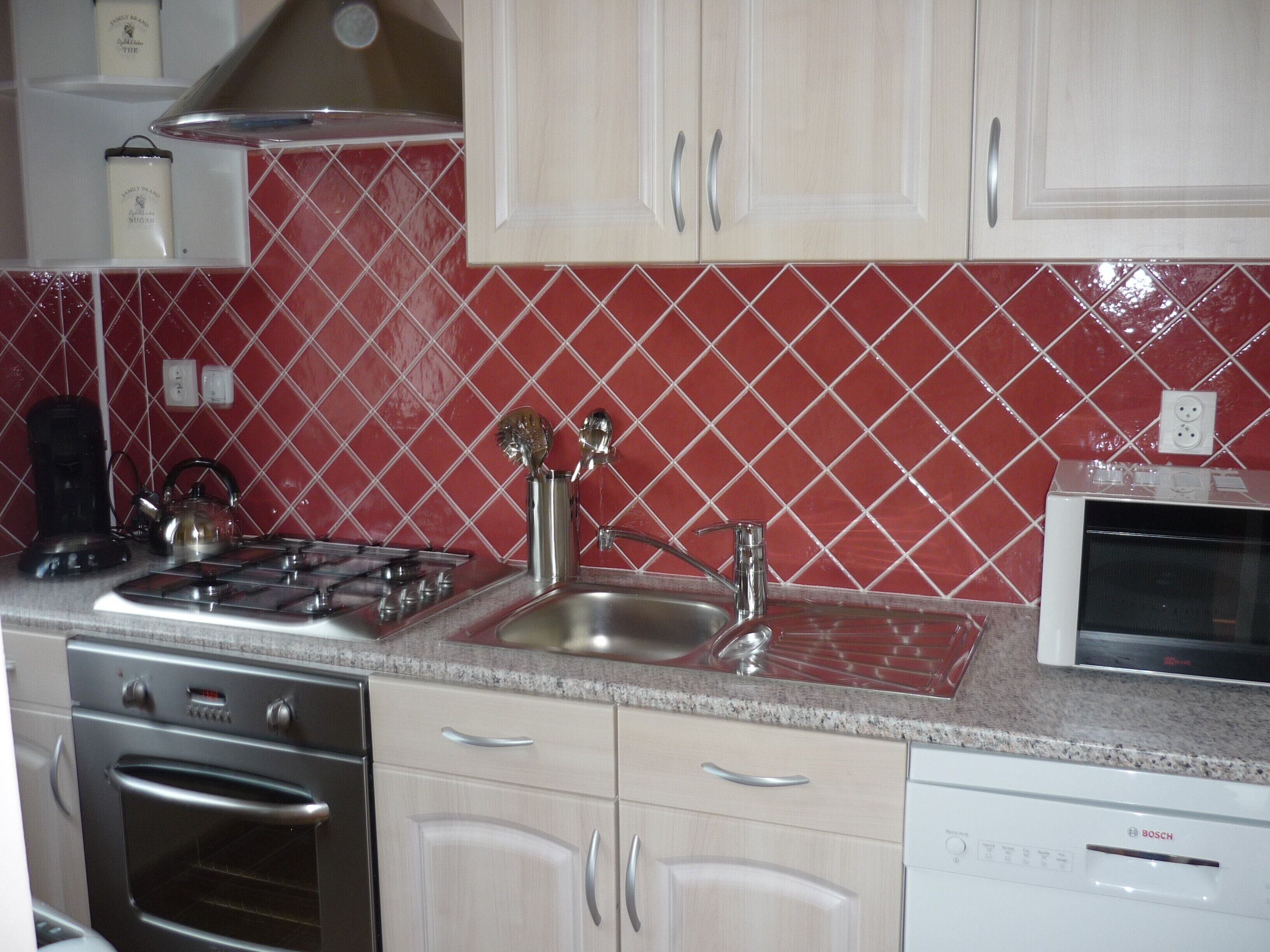 A kitchen with a gas stove, oven, sink, and dishwasher.