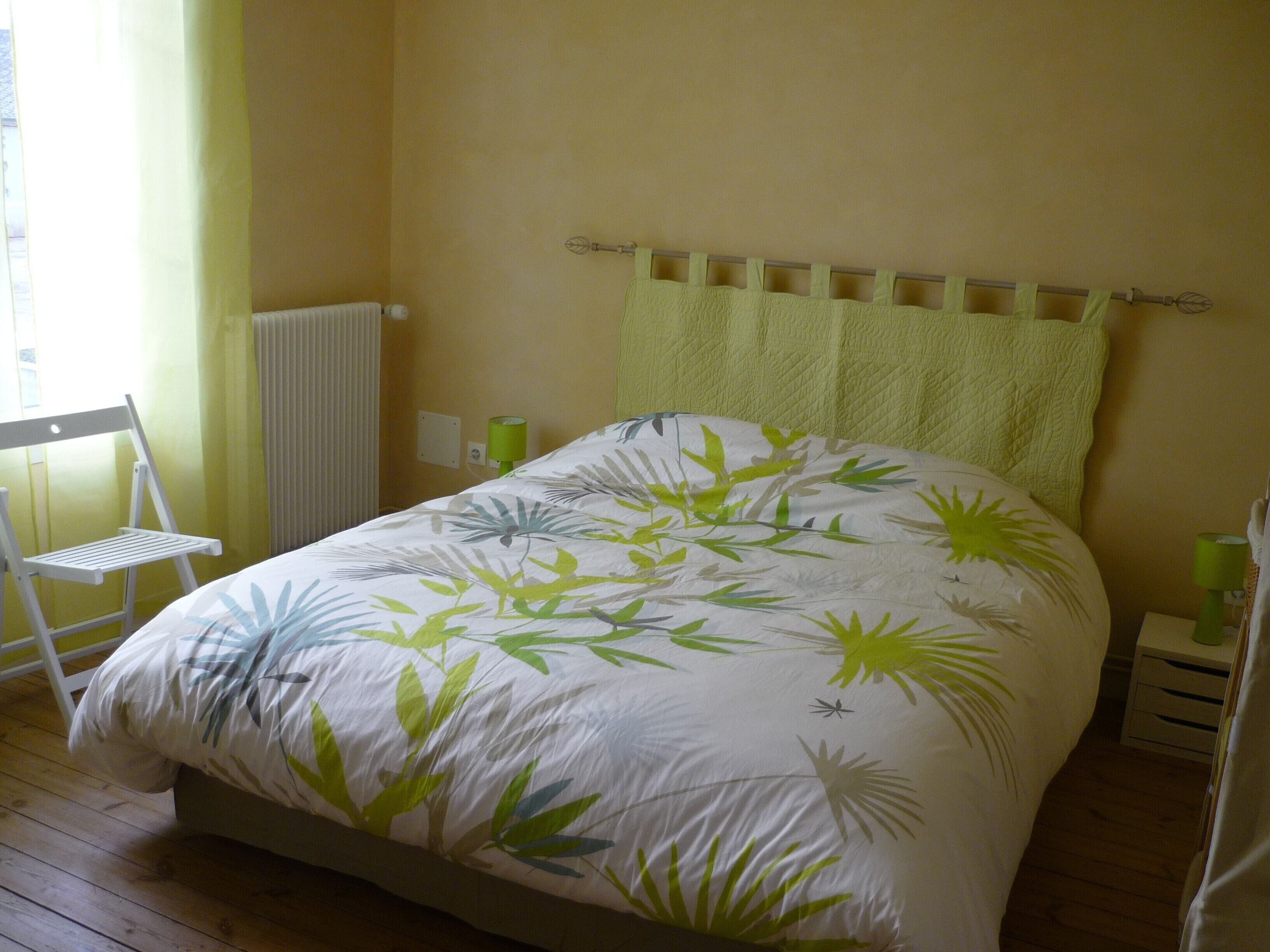 Une chambre à coucher comprenant un lit, une chaise, un radiateur et une table de chevet.