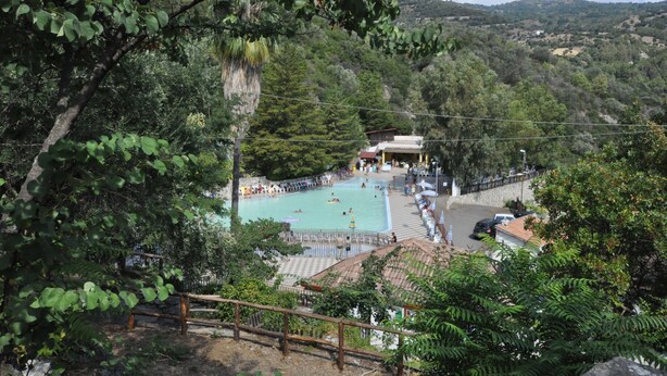 A swimming pool surrounded by lush greenery and hills in the background. - Agriturismo Pinelli (Plataci)