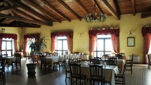 A spacious dining area with wooden beams, large windows with red curtains, and a chandelier. Tables are set for dining. - Agriturismo Pinelli (Plataci)