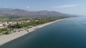 A coastal town with a beach, houses, and mountains in the background. - Agriturismo Pinelli (Plataci)