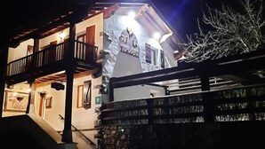 Un edificio de dos pisos con un balcón en el nivel superior, fachada de piedra y una escalera que conduce a la entrada.