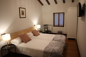 A double bed with a wooden headboard, two bedside tables with lamps, a framed picture on the wall, a window with curtains, and a radiator.
