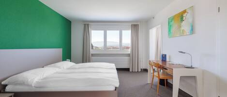 A hotel room with a bed, a desk, and a chair.