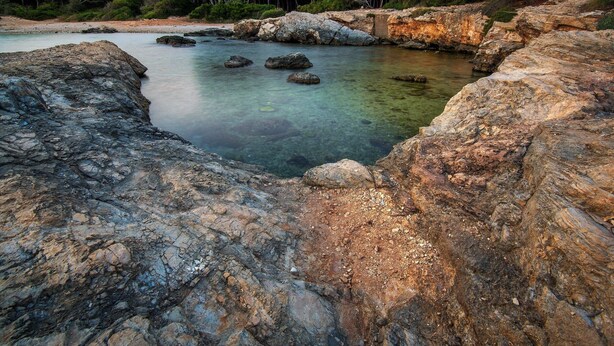 A rocky coastal landscape with clear water and dense greenery. - Palazzo Maritati (Nardò)