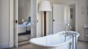 A bathroom with a freestanding bathtub, a large wall-mounted lamp, and a visible shower area. - Palazzo Maritati (Nardò)