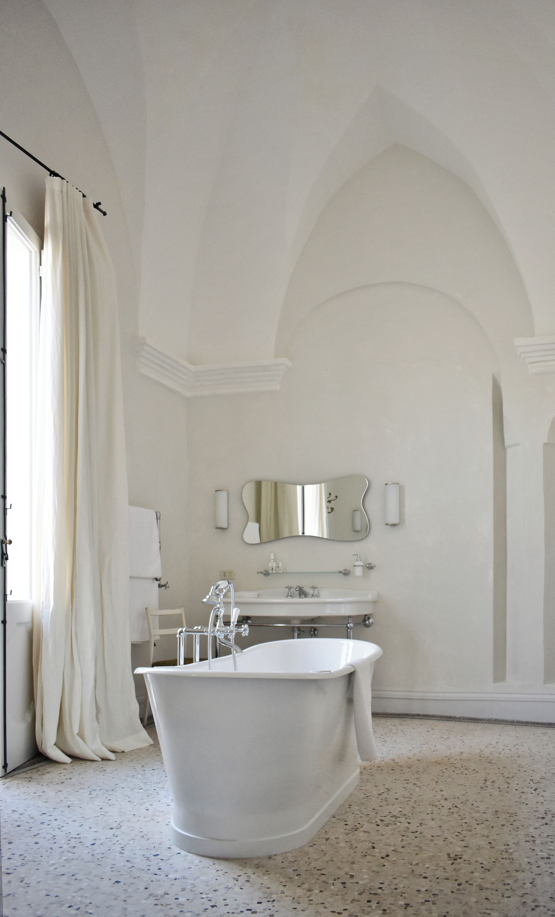 A bathroom with a freestanding bathtub, a large mirror, and a sink.