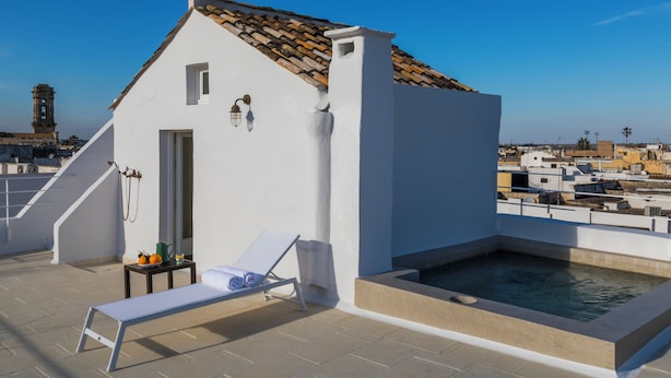 A rooftop terrace with a pool, a lounge chair, and a small table with a pitcher and oranges. - Palazzo Maritati (Nardò)