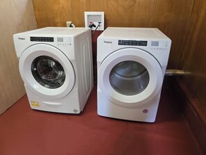 Two white Whirlpool front-loading washing machines side by side on a red floor.