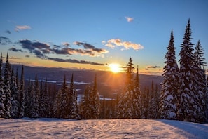 A snowy landscape with a sunset, evergreen trees, and a clear sky. - Morning Eagle #109 1 Bedroom Condo (Whitefish)