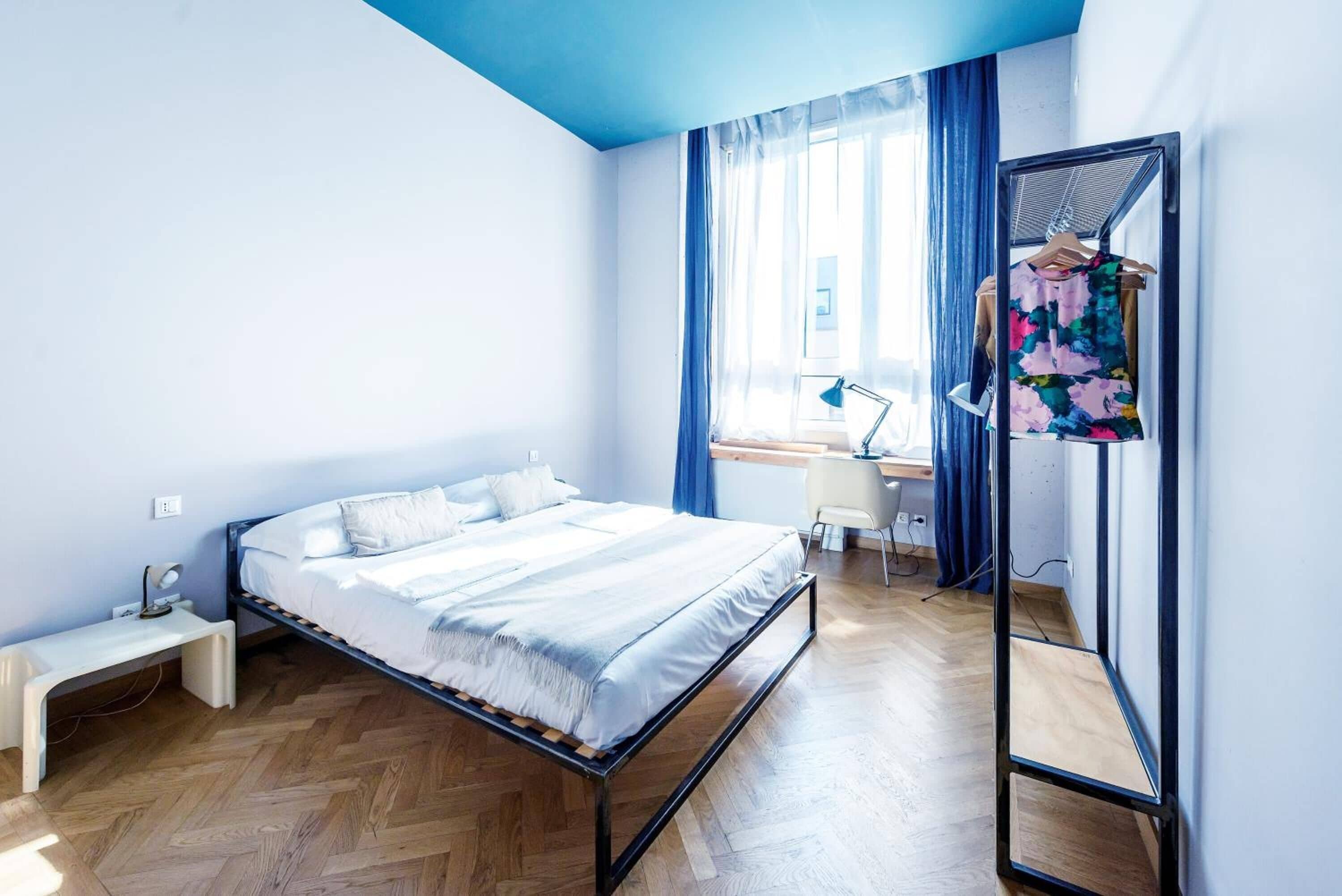 Un dormitorio con cama, mesita de noche, escritorio, silla y espejo.