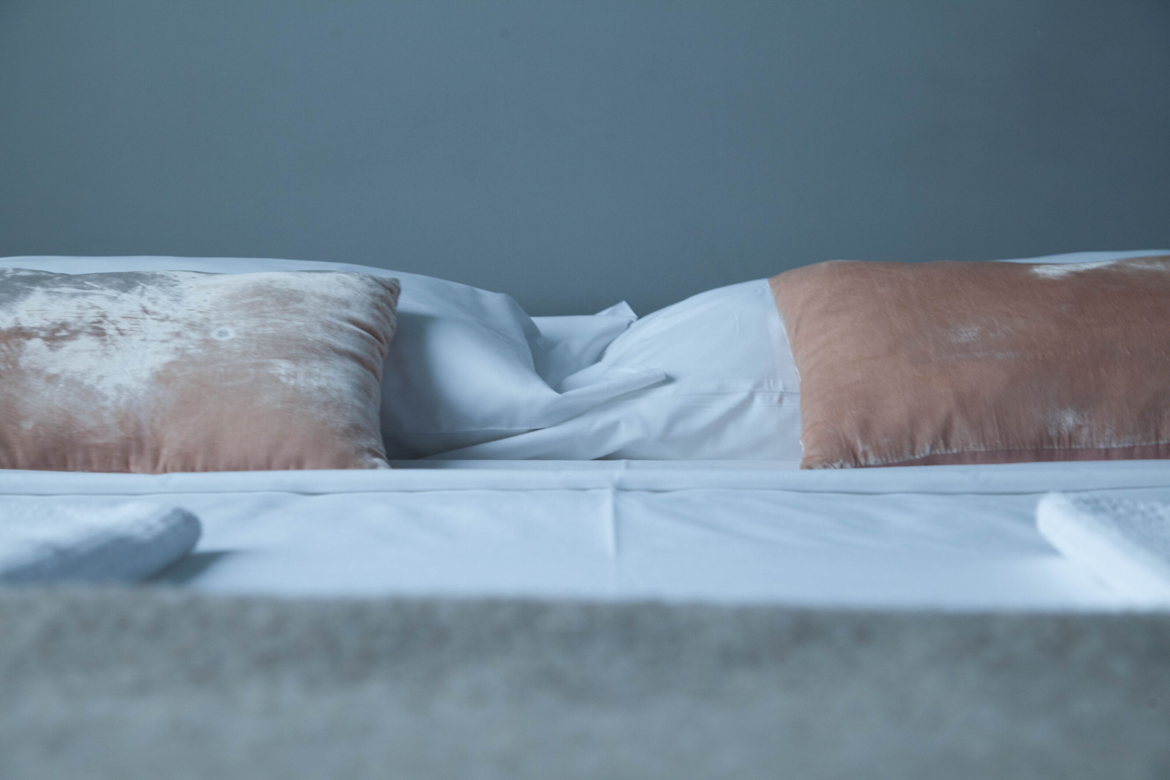 Ein Bett mit weißer Bettwäsche und zwei Kissen, eines mit braun-weißer Musterung.