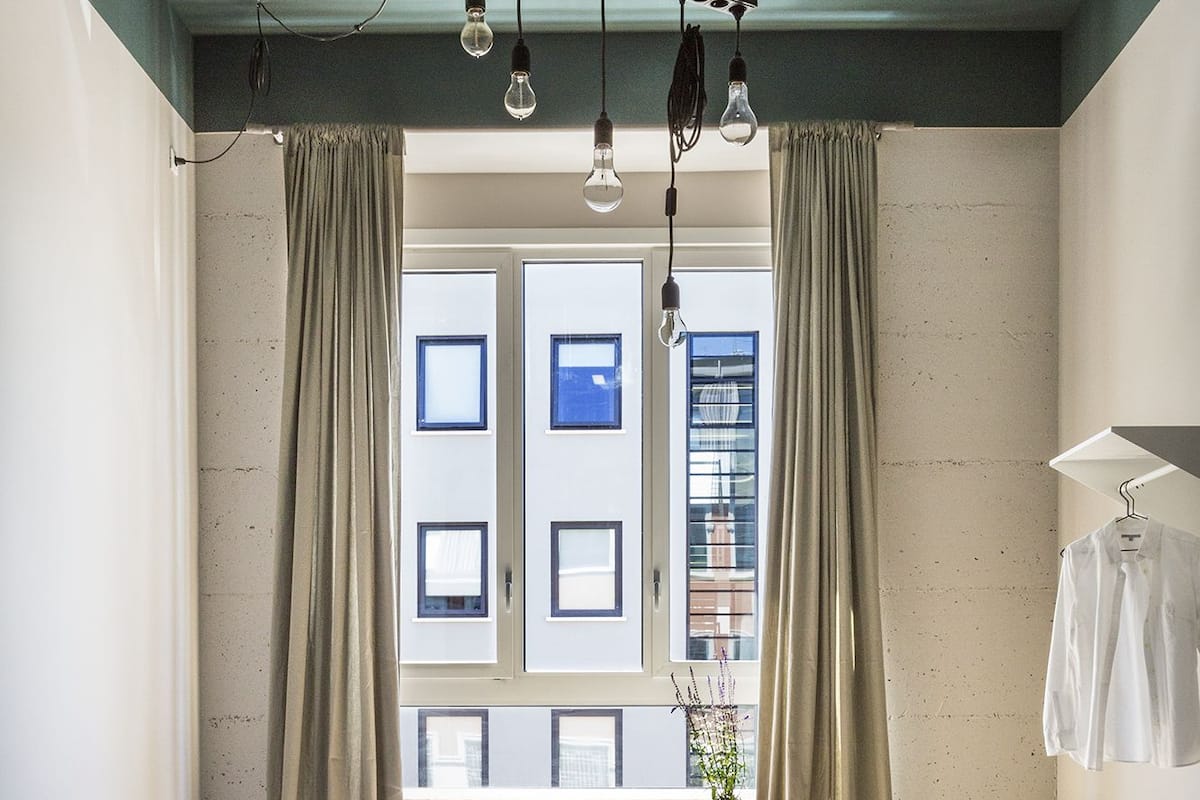 A modern hotel room with two beds, a desk, and a view of the city.