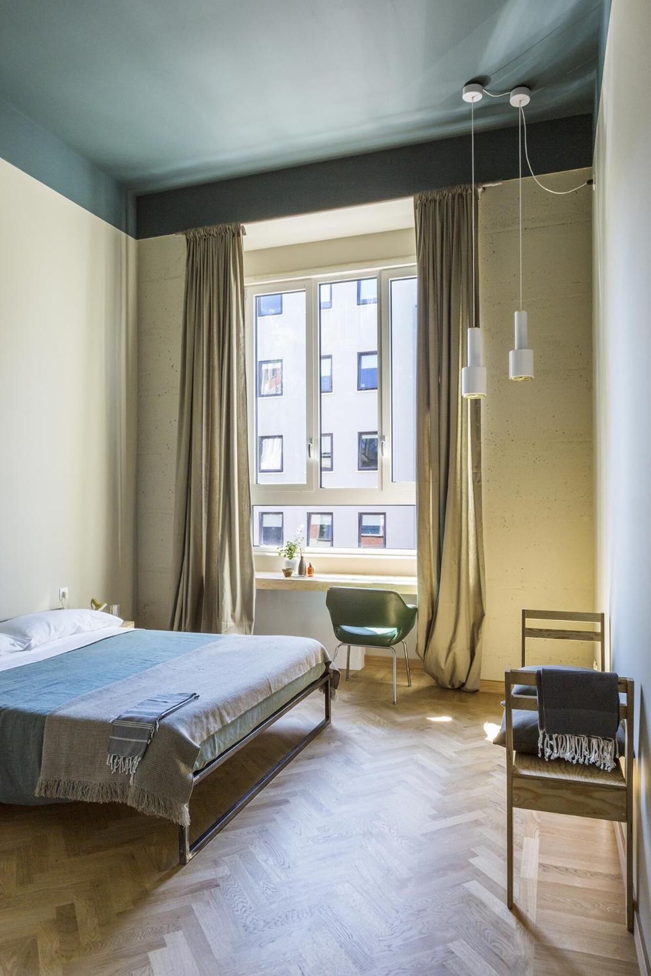 A bedroom with a bed, a desk, a chair, and a window with curtains.