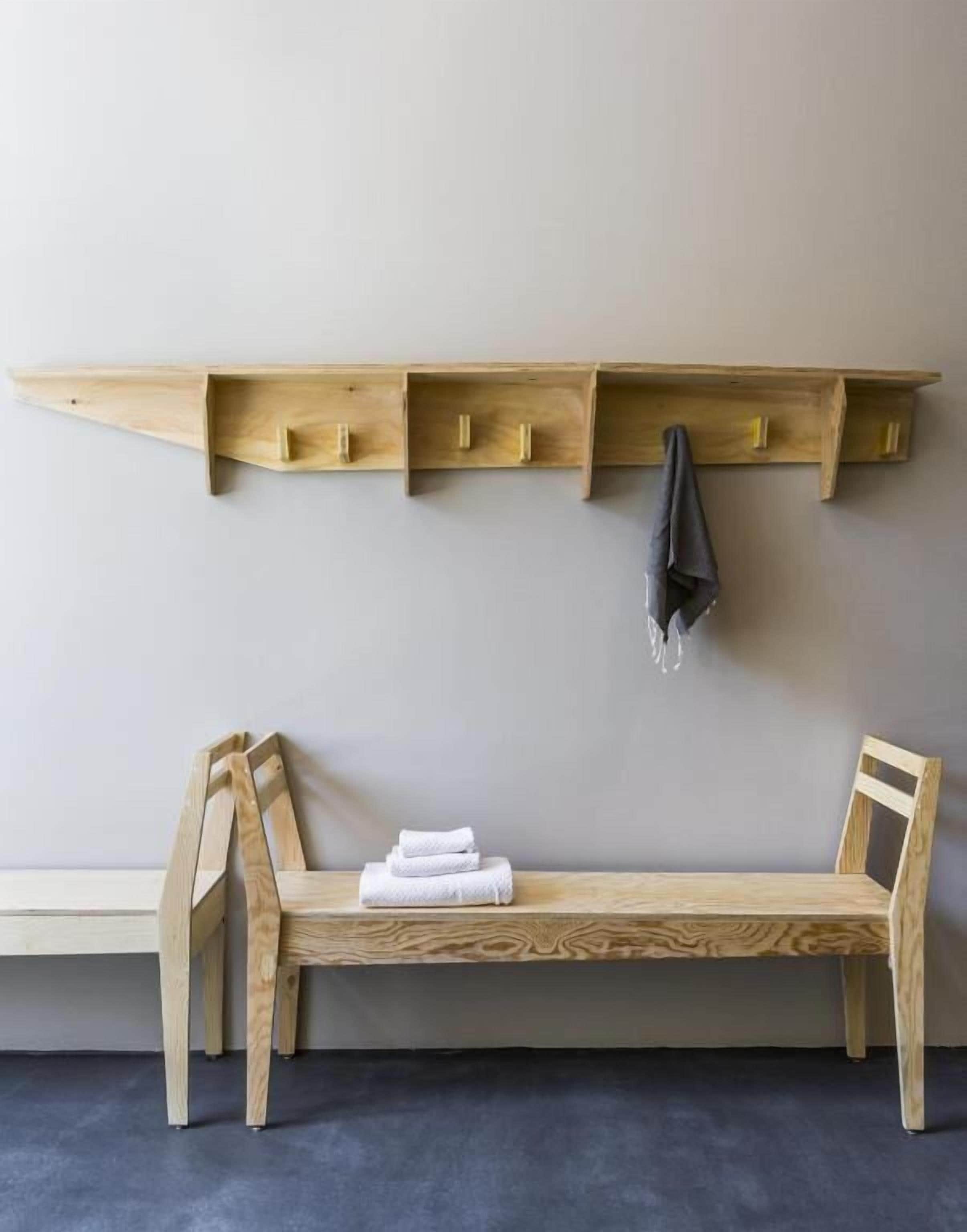 A wooden bench with a backrest and a shelf above it.