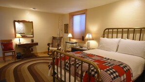 A bedroom with a bed, a chair, a desk, and a mirror.